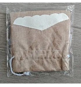Close-up of a Christmas burlap wine bottle bag with felt decoration in plastic packaging