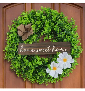 Detailed view of decorative green foliage wreath with Home Sweet Home wooden sign