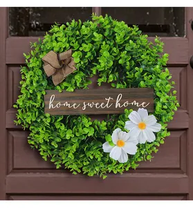 Detailed view of artificial green boxwood wreath with home sweet home sign on door
