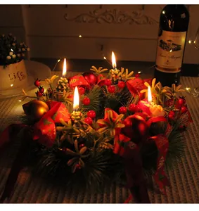 Festive detail of a Christmas wreath candle holder with warm lit candles and red berries