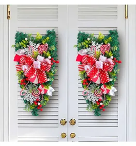 Traditional Christmas candy teardrop swag with red bows and snowflakes on a white door