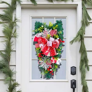Festive Christmas teardrop swag with red candy ornaments and a big bow for door decor