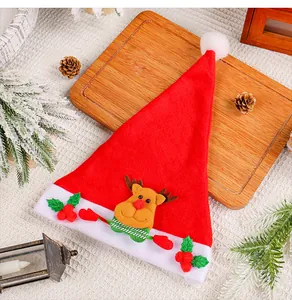 Cappello di Natale rosso con renna e bacche festive su vassoio in legno decorativo