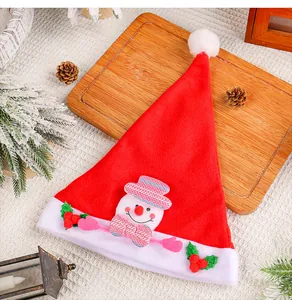 Primo piano di un cappello di Natale rosso con decorazione di pupazzo di neve e agrifoglio