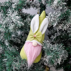 Gnomo di Pasqua in peluche con orecchie da coniglio e barba rosa su ramo di pino