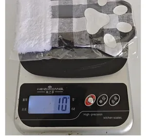Detailed view of plaid cat paw Christmas cutlery sleeve on a digital scale weighing 10g