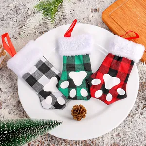 Three Christmas paw-shaped cutlery holders in plaid patterns on a festive plate setting