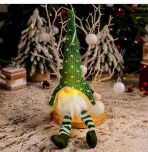 Detailansicht eines grünen gestrickten Weihnachtswichtels mit warmem LED-Licht und Beinen.