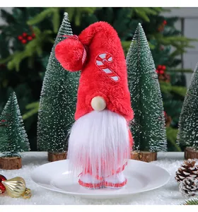 Close-up of plush Christmas gnome with candy cane embroidery on a tall red hat decoration.