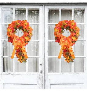 Detailed view of two autumn maple leaf wreaths with orange bows on a white door