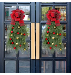 Detailed view of green mesh Christmas teardrop swags with red balls and plaid bows on door