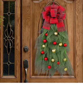 Festive Christmas teardrop wreath with red plaid bow and ornaments on a wooden door
