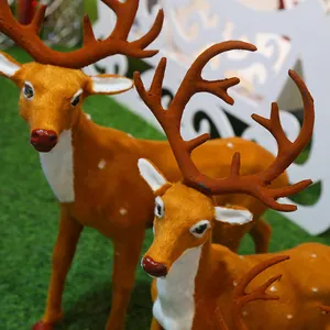 Détail rapproché de figurines de rennes de Noël floquées avec des bois marron sur herbe verte