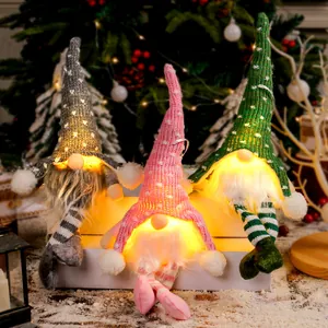 Festliche Weihnachtswichtel mit warmen Lichtern und Strickmützen auf einer Box.