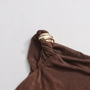 Vue détaillée de la boucle en métal doré poli sur une bandoulière plissée marron de qualité