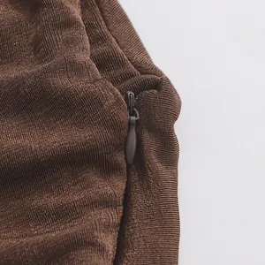 Gros plan sur la fermeture éclair invisible d'une robe longue plissée de couleur marron