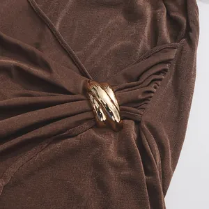 Gros plan sur la boucle en métal doré et les plis d'une robe marron sans manches
