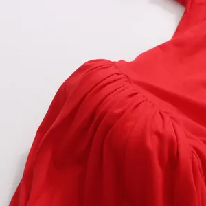 Dettaglio ravvicinato della spalla pieghettata di un elegante abito lungo rosso