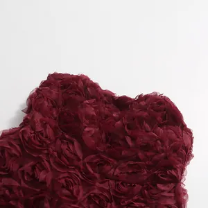 Detaillierte Nahaufnahme des burgunderroten 3D-Rosenstoffs an einer eleganten Abendrobe