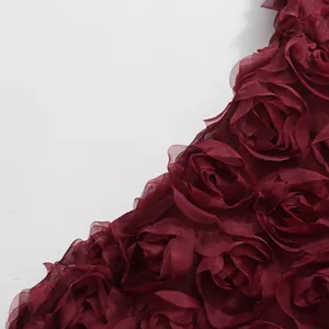 Nahaufnahme der weinroten 3D-Rosettenverzierung an einem eleganten Abendkleid aus Tüll