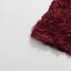 Detailansicht der weinroten 3D-Blumendekorationen an einem eleganten Abendkleid