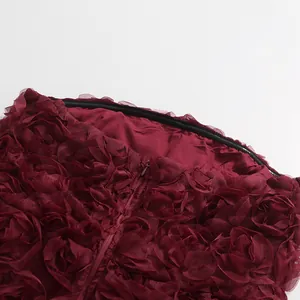 Detailansicht der 3D-Rosenapplikationen und des Reißverschlusses am weinroten Kleid.