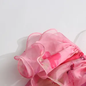 Nahaufnahme der rosa floralen Rüschendetails an einem leichten Sommer-Strandkleid.