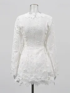 Vestido corto blanco de manga larga con bordados florales y cordones laterales.