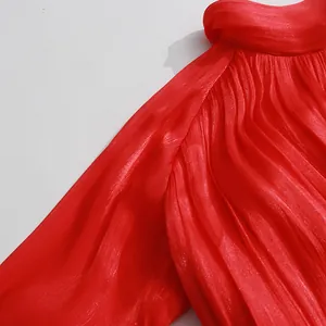 Close-up detail showing the elegant red pleated fabric texture and stand collar of the dress