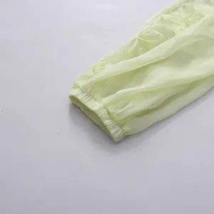 Gros plan d'une manche de robe en mousseline jaune pâle avec broderies florales