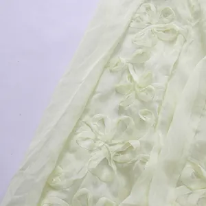 Vue macro de la broderie florale délicate et du tissu en mousseline de soie jaune pâle