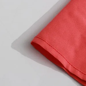 Detailed close-up view showing the vibrant red fabric and neat stitching of a retro dress hem