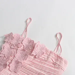 Close-up detail of a pink pleated camisole dress featuring delicate 3D floral applique