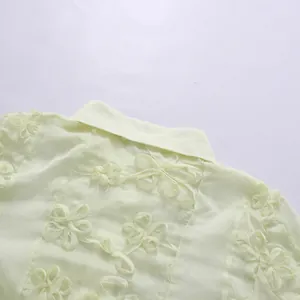 Gros plan sur la broderie florale du col d'une robe en mousseline jaune clair de style français