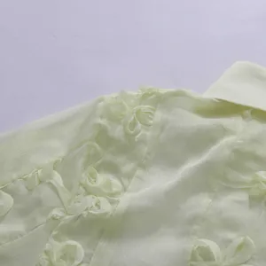 Détail rapproché d'une robe en mousseline jaune pâle avec broderie florale en 3D