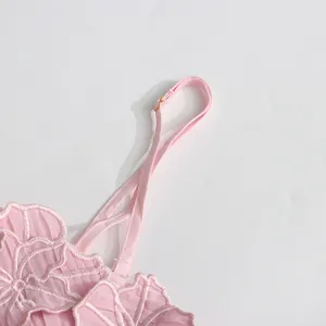 Close-up of pink floral lace embroidery and adjustable shoulder strap on dress