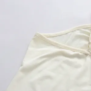Vue macro détaillée montrant les coutures fines et l'encolure d'une robe en mousseline crème