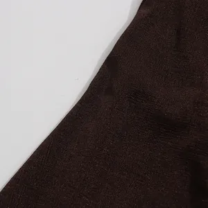 Makroansicht der tiefbraunen gerippten Strickstofftextur eines eleganten ärmellosen Kleides.