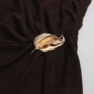 Detaillierte Makroansicht einer eleganten goldmetallenen Schnalle an einem dunkelbraunen Kleid