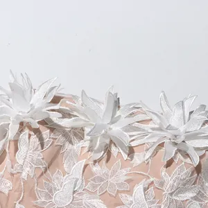 Close-up detail showing white 3D floral embroidery on nude mesh evening dress fabric