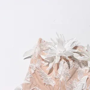 Close-up detail of exquisite white 3D floral embroidery on nude mesh fabric