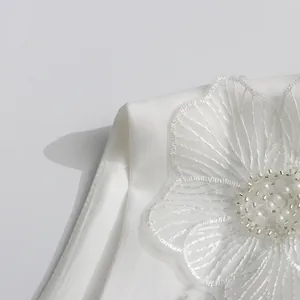 Gros plan sur la broderie florale blanche et les perles d'une robe élégante