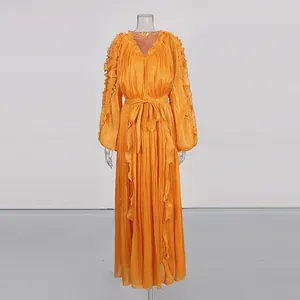 Detail view of an orange pleated maxi dress with silky fabric and ruffle details.