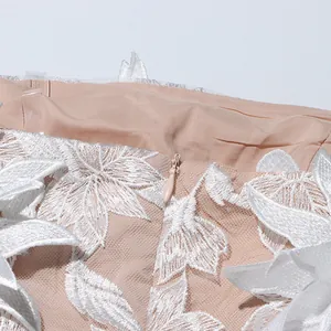 Macro view of the invisible zipper and intricate white floral embroidery on a mesh dress