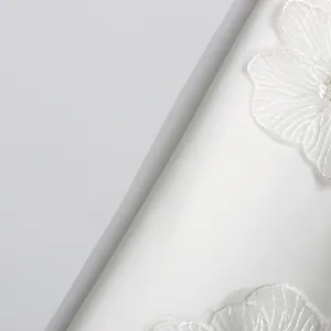 Gros plan sur le tissu élégant d'une robe en satin blanc avec broderies florales