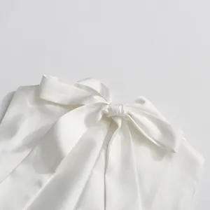 Détail d'une robe blanche sans manches élégante avec un grand nœud en satin au col
