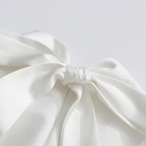 Gros plan d'un élégant nœud en satin blanc sur une robe de soirée sans manches