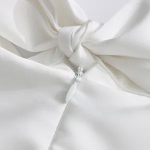 Gros plan détaillé de la fermeture éclair invisible et du nœud sur une robe de soirée blanche