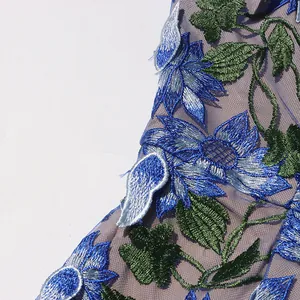 Detailed view of intricate blue flower and green leaf embroidery on mesh dress fabric