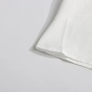Gros plan sur l'ourlet d'une robe trapèze blanche sans manches avec coutures soignées.